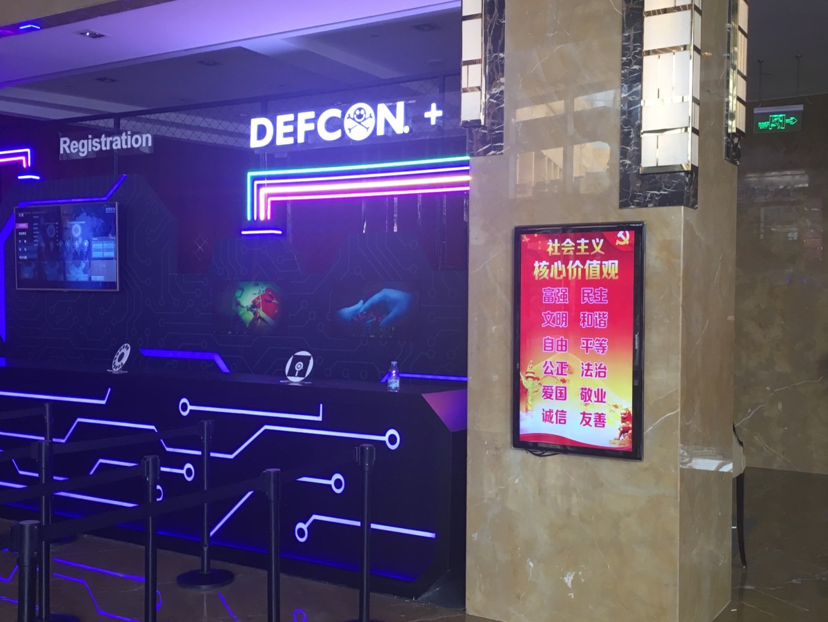 DEF CON China registration booth next to digital sign listing 'the core values
of socialism'.